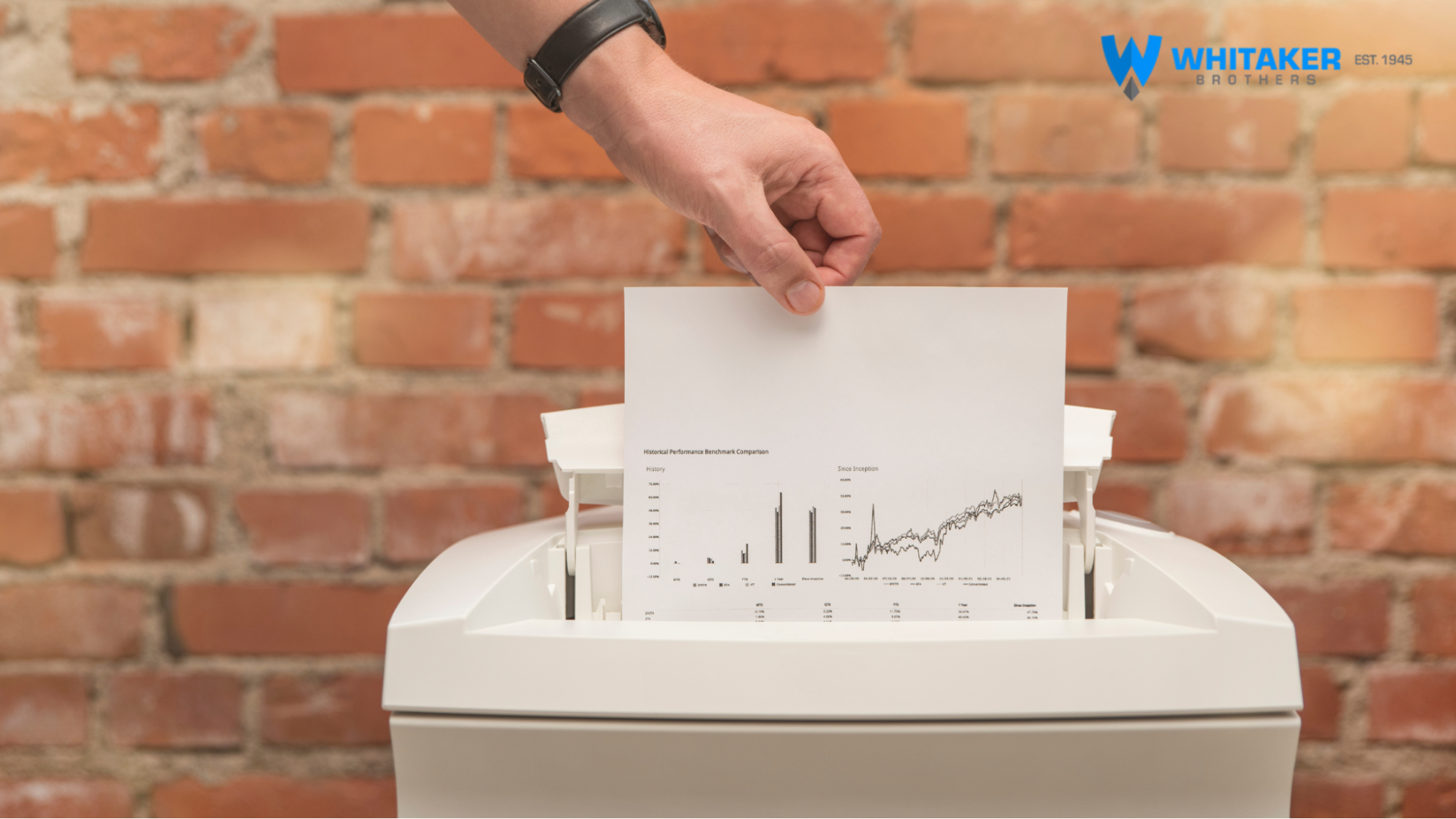 Image of a man's hand placing a piece of paper with confidential information into a shredder.